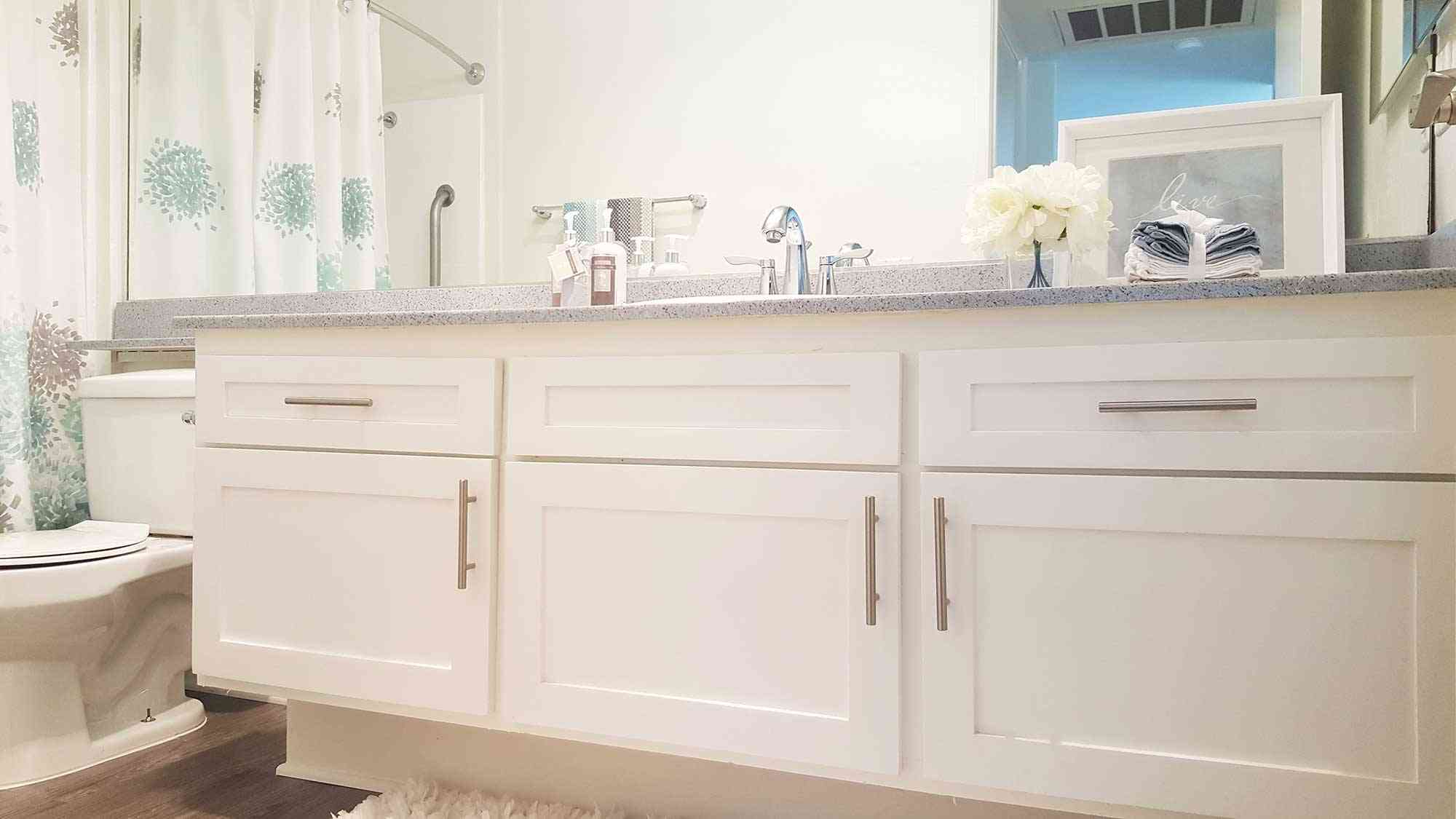 bathroom vanity with white cabinets and granite countertop